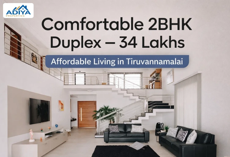 Modern living room interior of a 2BHK duplex house in Tiruvannamalai featuring a white color theme, staircase, and contemporary furniture.